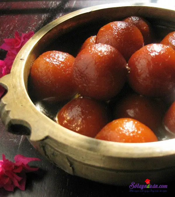 Bước 5: - Trong l&uacute;c chi&ecirc;n, bạn nhớ đảo li&ecirc;n tục để vi&ecirc;n b&aacute;nh ch&iacute;n v&agrave;ng đều v&agrave; tr&aacute;nh bị ch&aacute;y. - Khi thấy b&aacute;nh đ&atilde; ch&iacute;n th&igrave; m&igrave;nh vớt ra, để cho r&aacute;o dầu 1 ch&uacute;t rồi thả v&agrave;o phần nước đường ng&acirc;m &iacute;t nhất trong v&ograve;ng 2 tiếng. - Cuối c&ugrave;ng, rắc th&ecirc;m hạt hạnh nh&acirc;n gi&atilde; nhỏ b&ecirc;n tr&ecirc;n l&agrave; được. 6